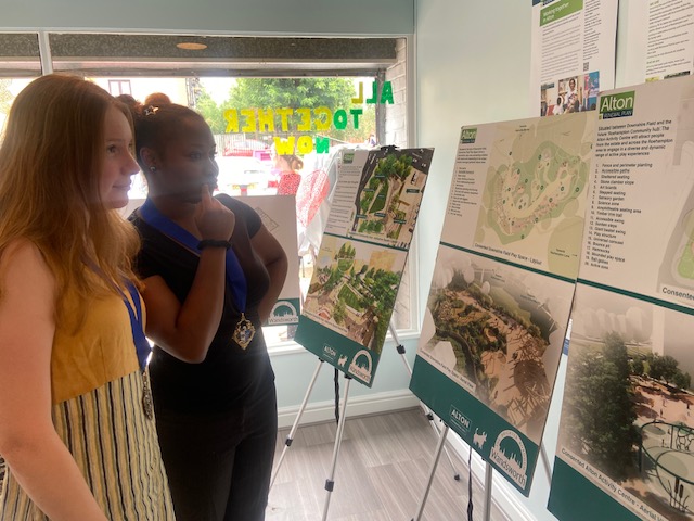 Two people are pictured studying exhibition boards which introduce the Alton Renewal plans.