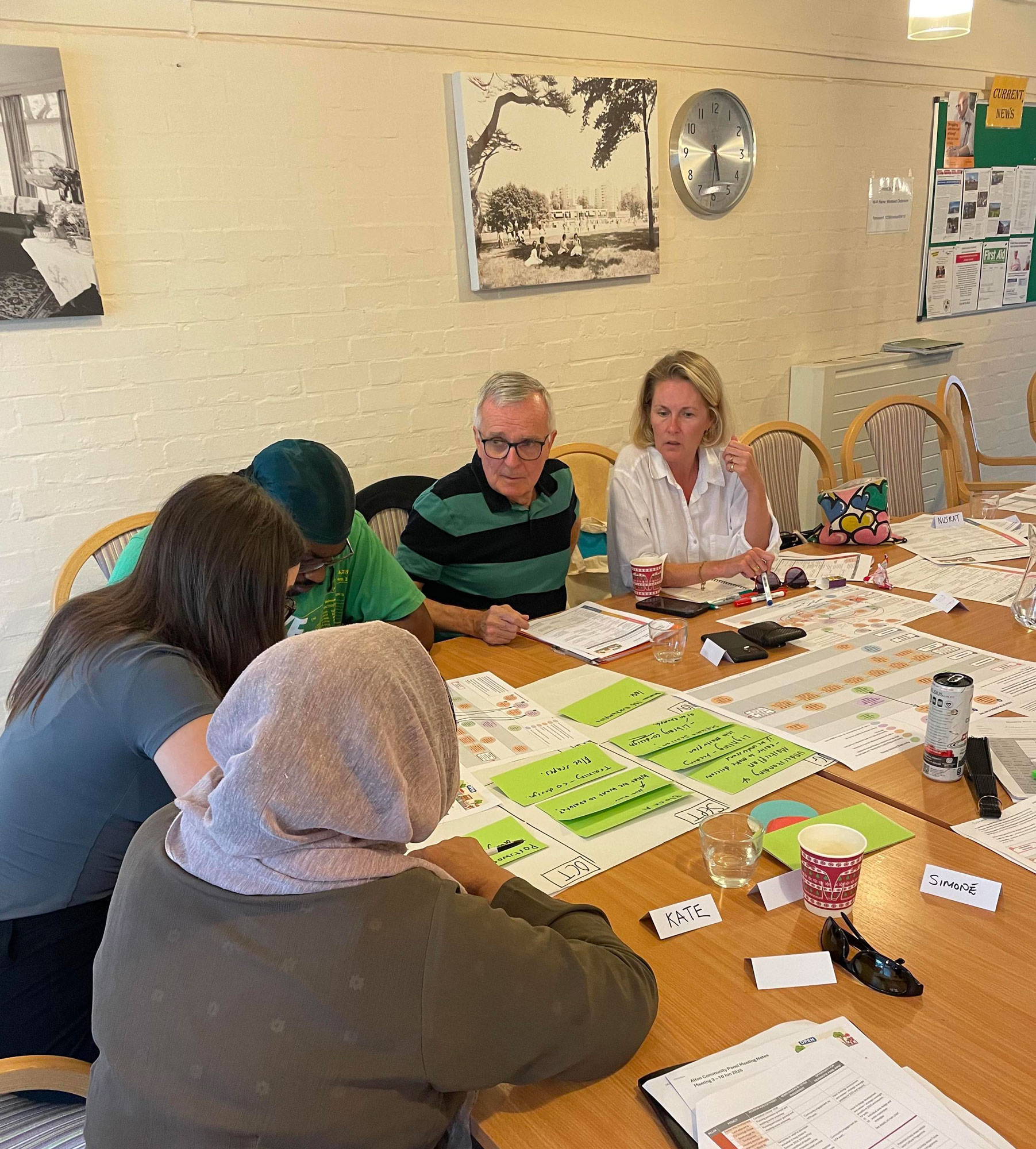 Alton Community Panel members are pictured sitting around a table, with notes in front of them, having a discussion.