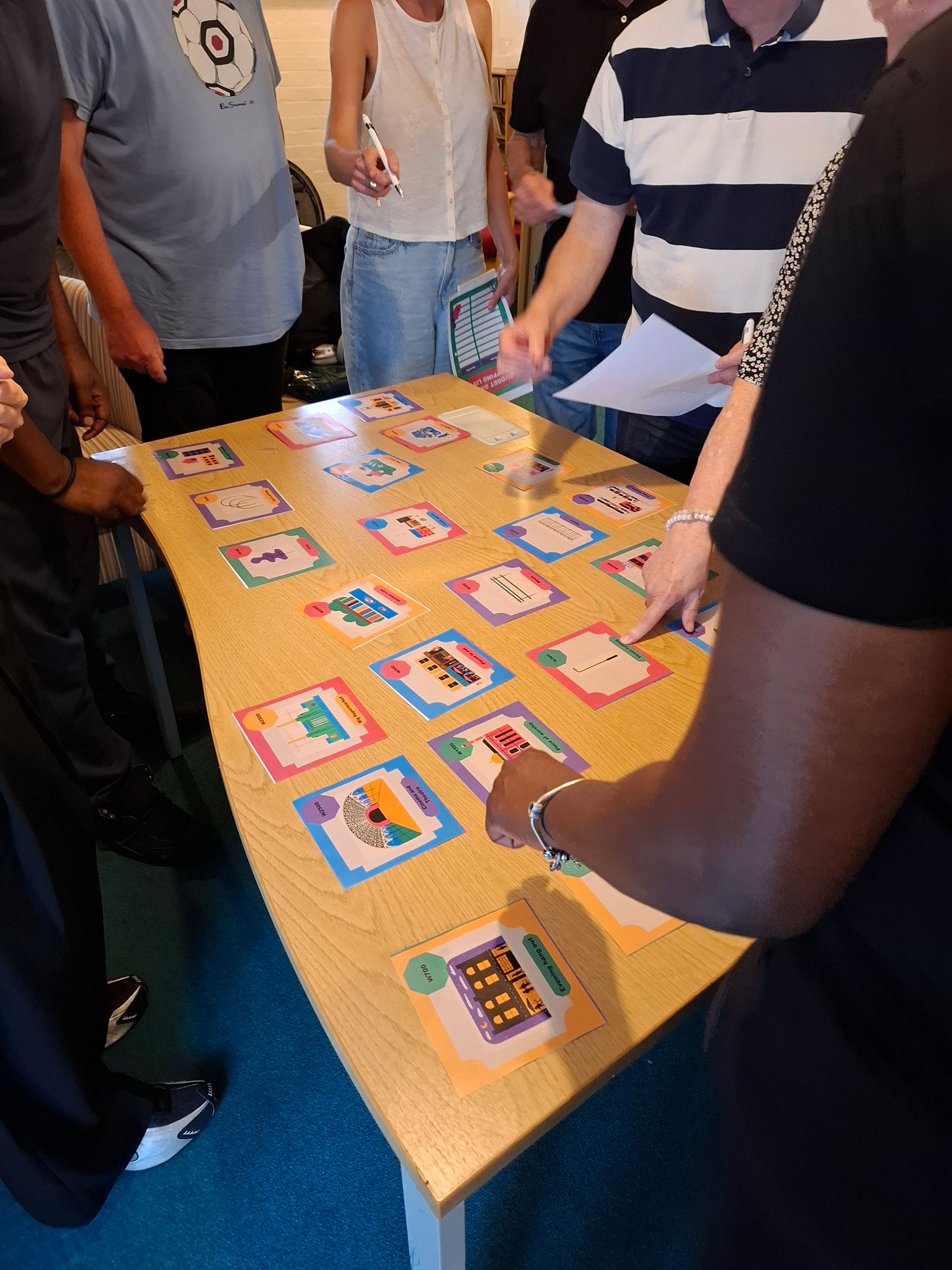 Images are laid out on a table and members of the Alton Community Panel are standing round the table reviewing the images.