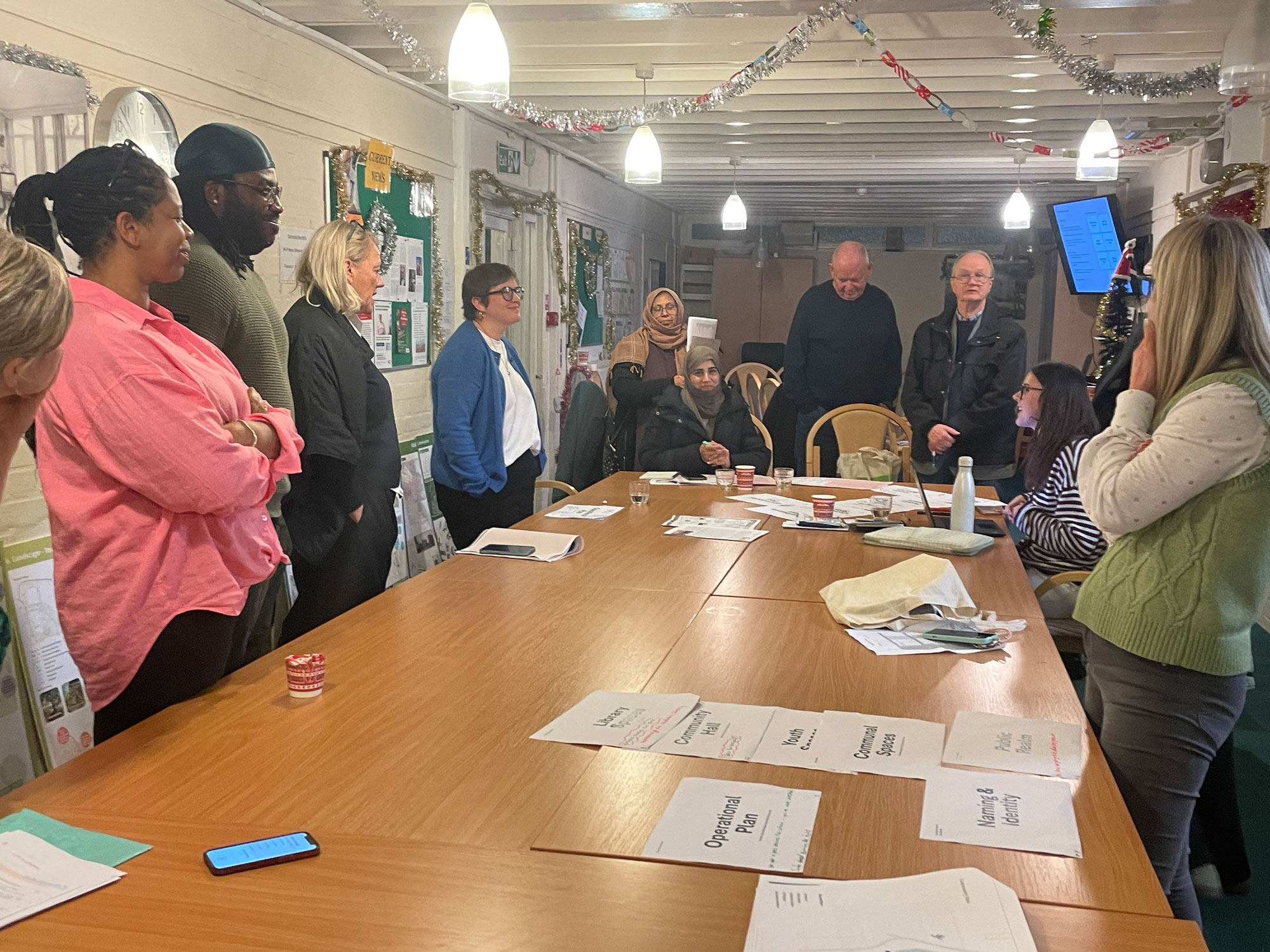 Alton Community Panel members are pictured sitting and standing around a table, having a discussion.