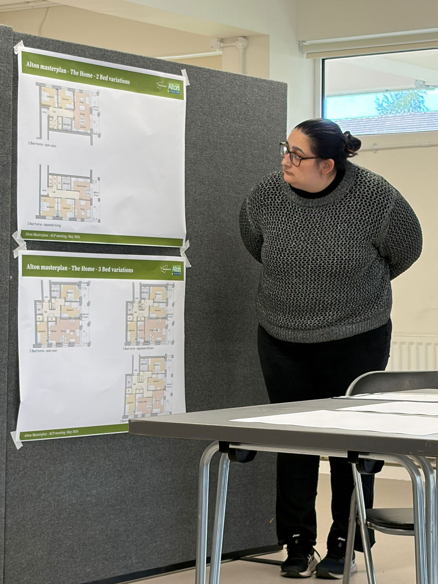 A person is pictured standing next to a display board, looking at layout plans for two and three bedroom flats.
