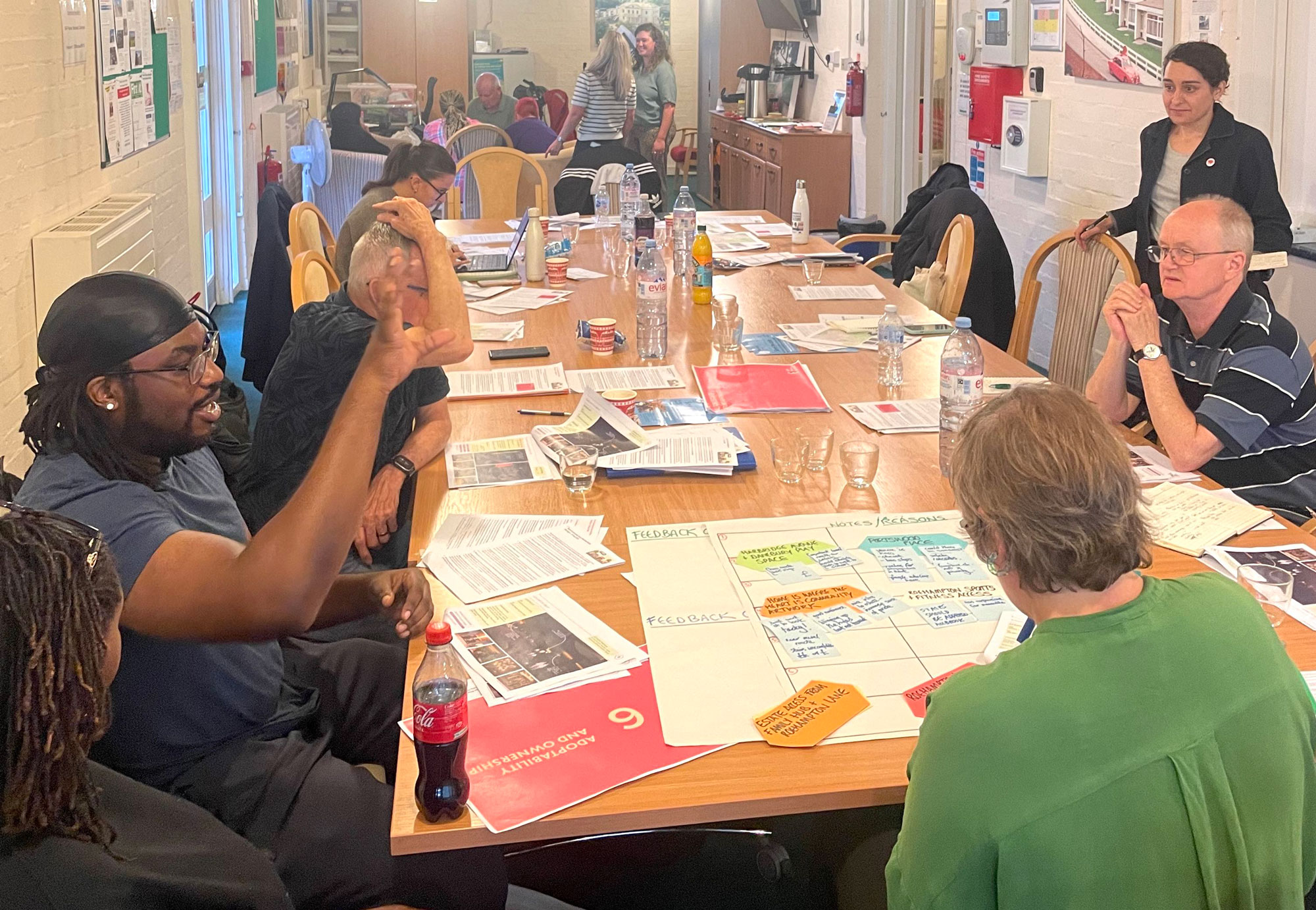 A group of people are sitting around a large table having a discussion.