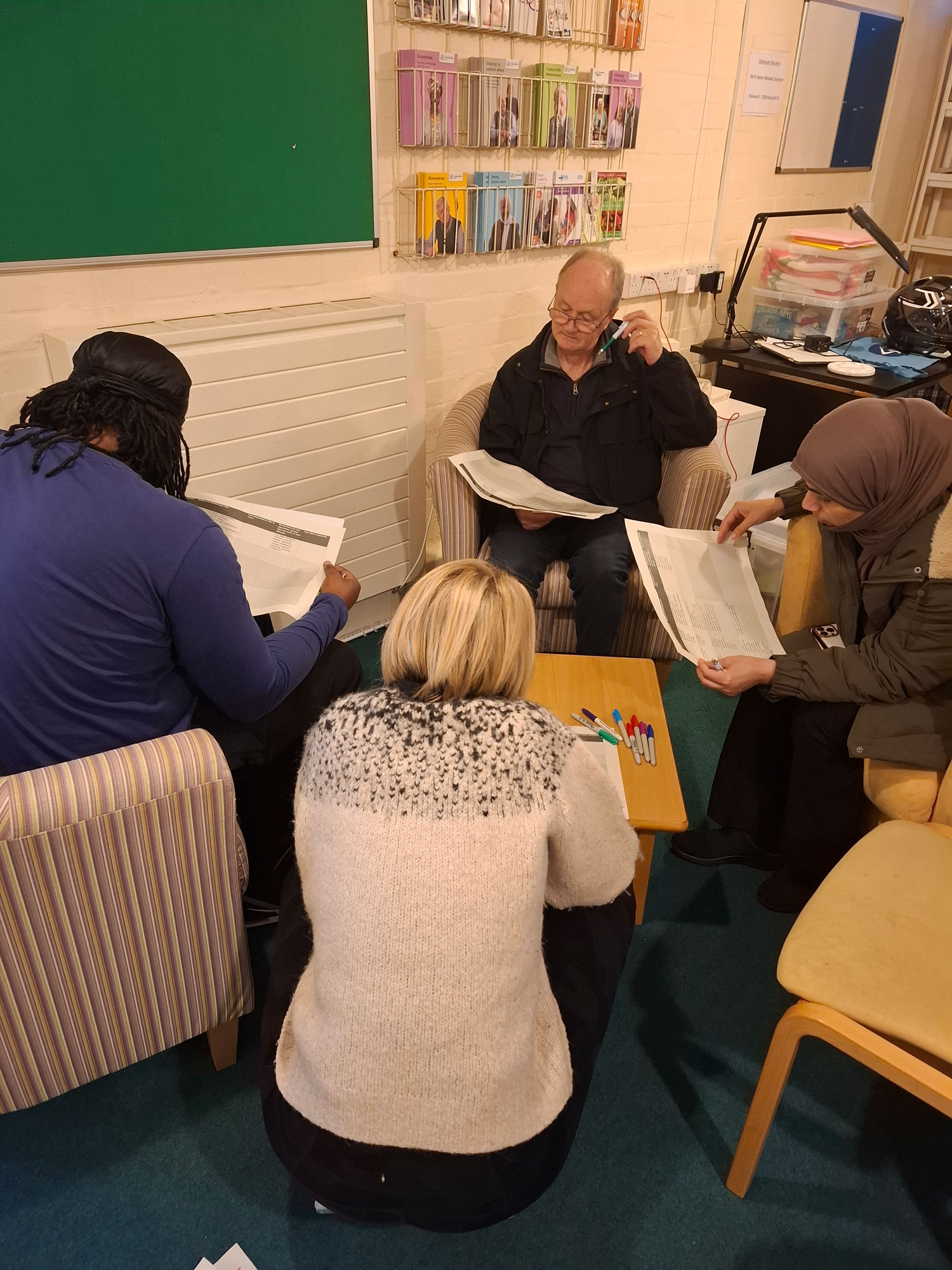 This picture shows a group of four people sitting round a coffee table, studying documents.