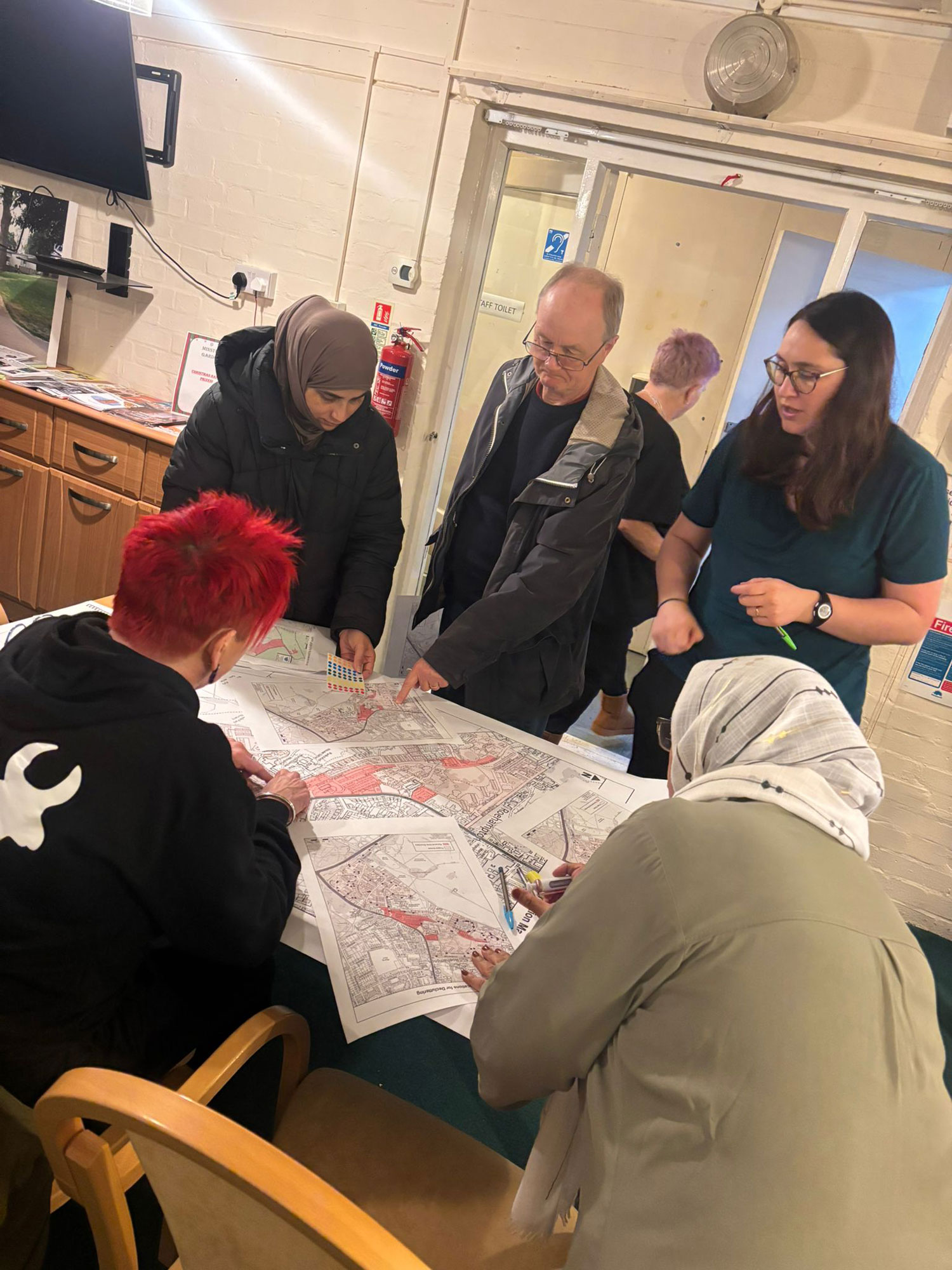 Members of the Alton Community Panel are pictured standing over a table, reviewing development plans and having a discussion.
