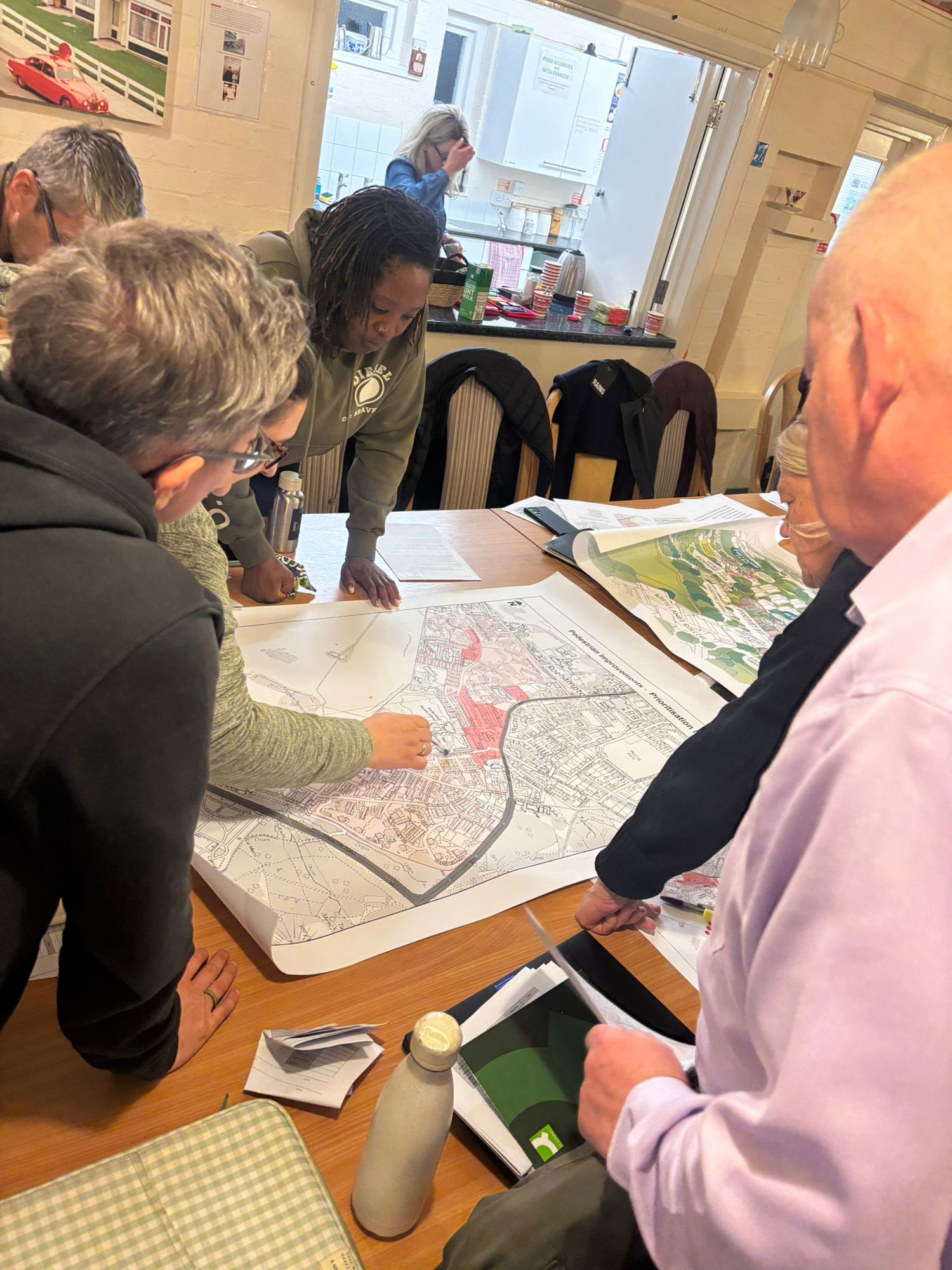 Members of the Alton Community Panel are pictured standing over a table, reviewing development plans and having a discussion.