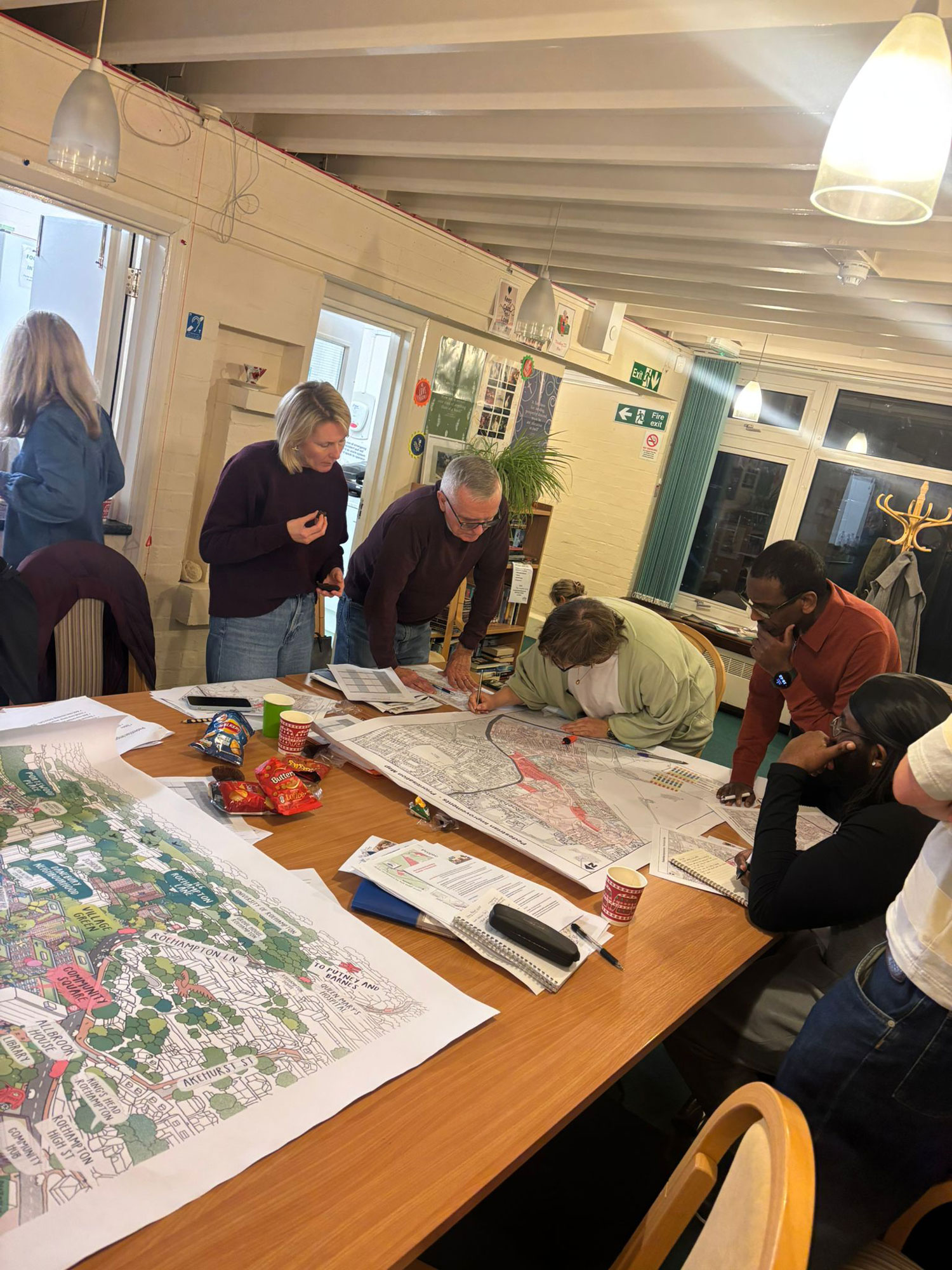 Members of the Alton Community Panel are pictured standing over a table, reviewing development plans and having a discussion.