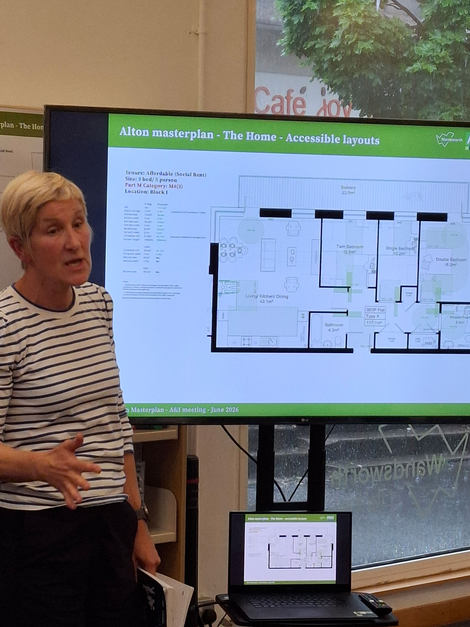 Picture of a presenter, standing in front of a presentation screen, talking about accessible home layouts.