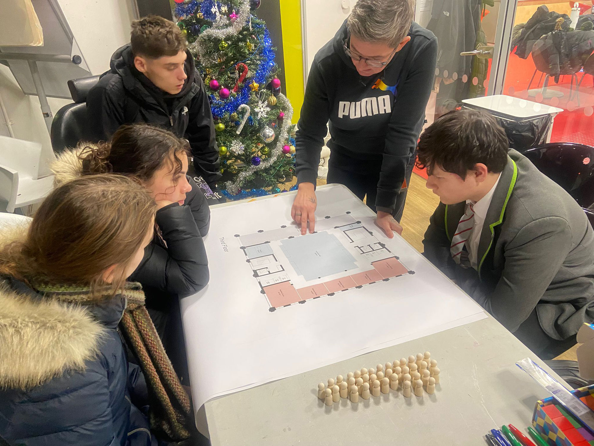 Members of the Youth Advisory Panel are pictured sitting around a table, looking at plans for the third floor of Block A - the new community hub